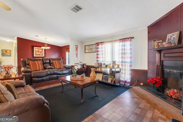 living room featuring wood walls, a textured ceiling, lofted ceiling, and a tiled fireplace