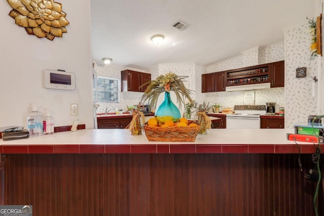 kitchen with kitchen peninsula, a textured ceiling, and white electric range