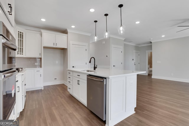 kitchen with a sink, appliances with stainless steel finishes, ornamental molding, and light wood-type flooring