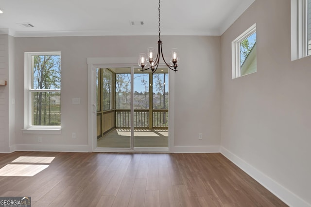 unfurnished dining area featuring an inviting chandelier, baseboards, wood finished floors, and visible vents