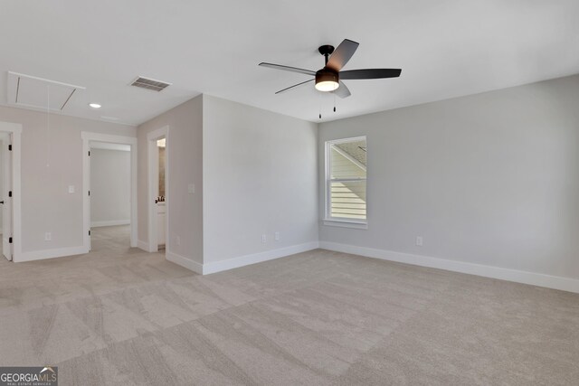 unfurnished room featuring light carpet, attic access, a ceiling fan, baseboards, and visible vents