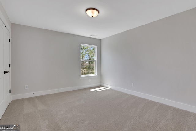 empty room with baseboards, light carpet, and visible vents