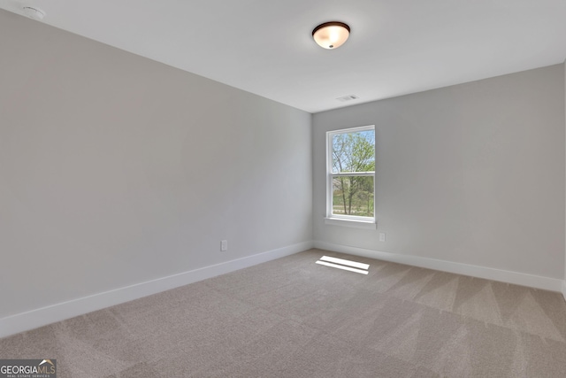 empty room featuring baseboards, visible vents, and light carpet