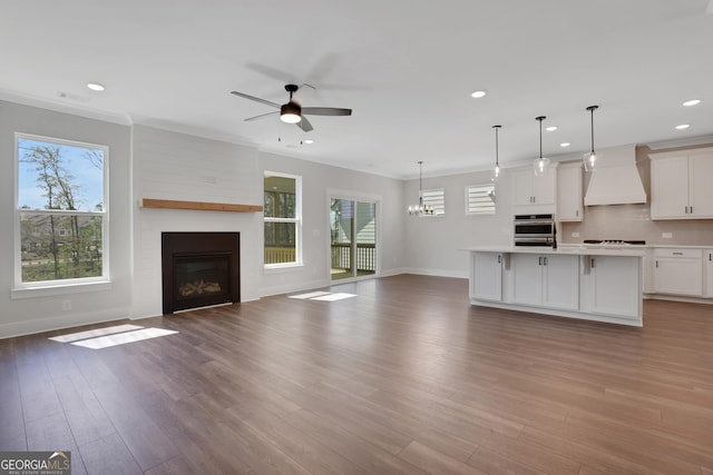 kitchen with ceiling fan with notable chandelier, a healthy amount of sunlight, custom range hood, and open floor plan
