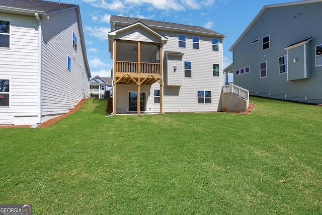 rear view of property featuring a lawn, ceiling fan, and a sunroom
