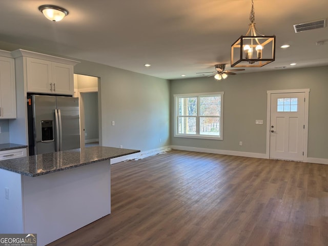 kitchen featuring white cabinetry, dark hardwood / wood-style floors, stainless steel fridge, dark stone counters, and ceiling fan with notable chandelier