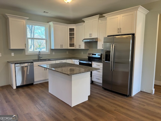 kitchen with dark wood-type flooring, white cabinets, sink, appliances with stainless steel finishes, and a kitchen island