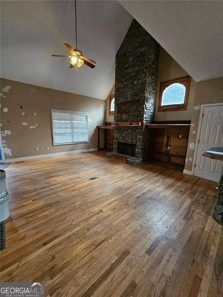 unfurnished living room featuring a stone fireplace, a wealth of natural light, and hardwood / wood-style flooring