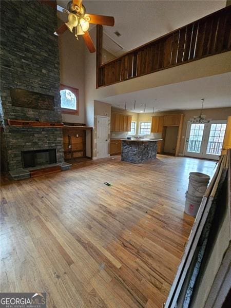 unfurnished living room with ceiling fan, a fireplace, a healthy amount of sunlight, and light hardwood / wood-style flooring