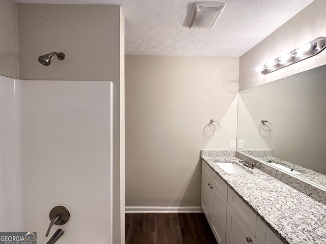 bathroom with wood-type flooring, vanity, and a textured ceiling