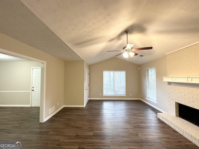 unfurnished living room with a brick fireplace, vaulted ceiling, ceiling fan, a textured ceiling, and dark hardwood / wood-style flooring