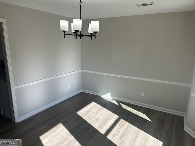 unfurnished dining area featuring a chandelier and dark wood-type flooring