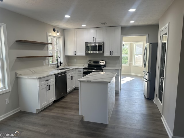 kitchen featuring white cabinetry, plenty of natural light, a kitchen island, and appliances with stainless steel finishes