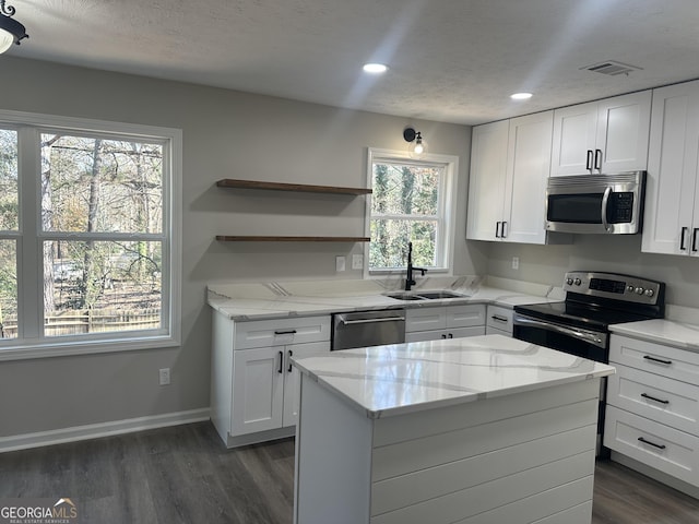 kitchen featuring stainless steel appliances, white cabinetry, a wealth of natural light, and sink