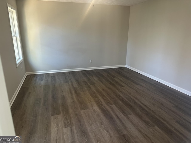 unfurnished room featuring dark wood-type flooring and a textured ceiling