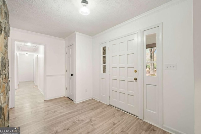 foyer featuring light hardwood / wood-style floors, crown molding, and a textured ceiling