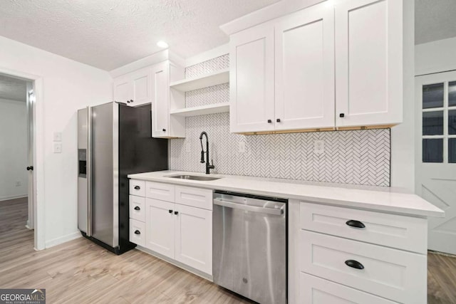 kitchen with white cabinetry, sink, stainless steel appliances, and light wood-type flooring