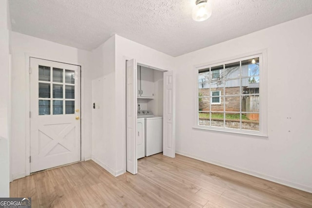 interior space with cabinets, washing machine and clothes dryer, a textured ceiling, and light hardwood / wood-style flooring