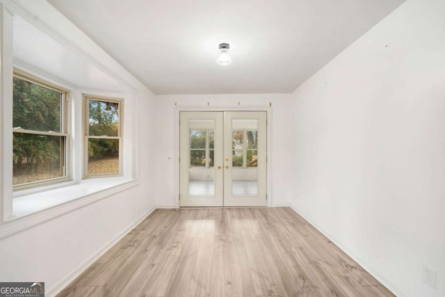 empty room with light hardwood / wood-style flooring, a wealth of natural light, and french doors