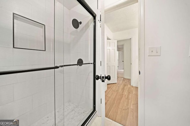 bathroom with wood-type flooring and an enclosed shower