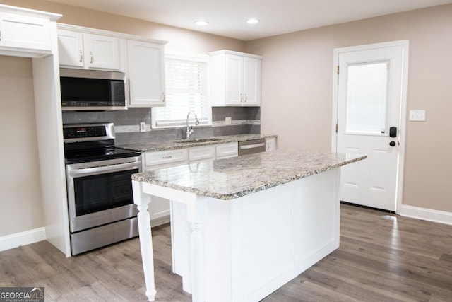 kitchen featuring white cabinets, decorative backsplash, a center island, and appliances with stainless steel finishes