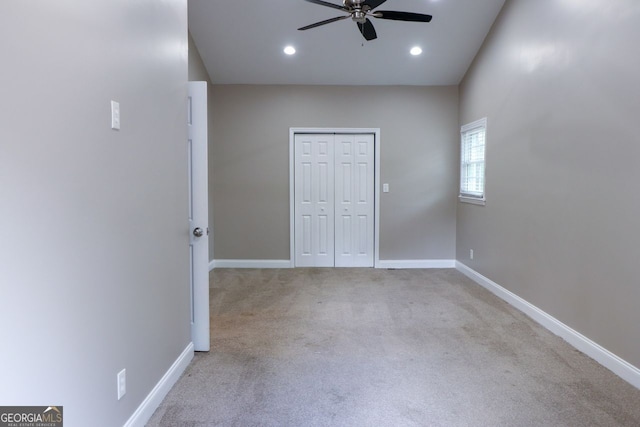 unfurnished bedroom with ceiling fan, light colored carpet, and a closet