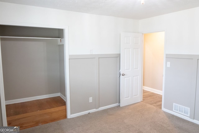 unfurnished bedroom with light carpet and a closet