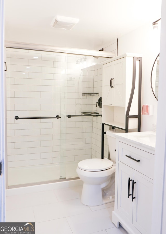 bathroom featuring tile patterned floors, vanity, a shower with shower door, and toilet