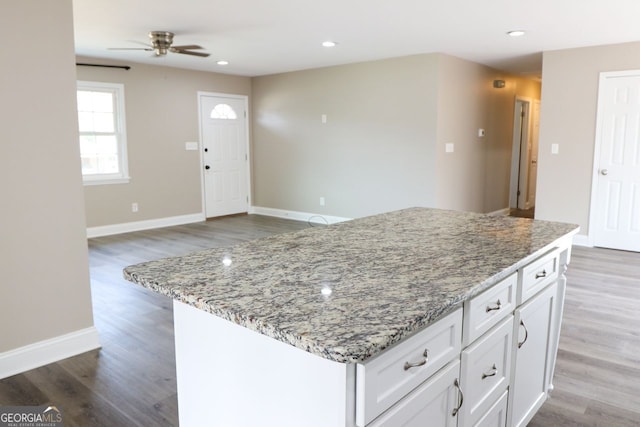 kitchen featuring light stone countertops, white cabinets, and hardwood / wood-style flooring