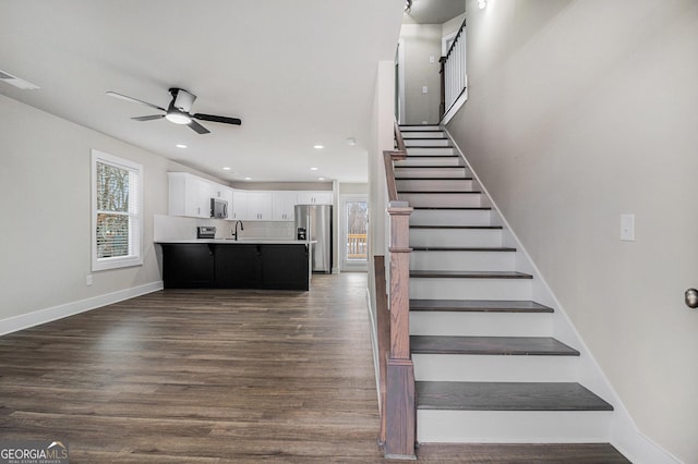 staircase with hardwood / wood-style floors and ceiling fan