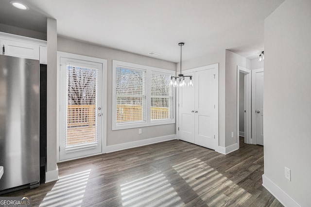 unfurnished dining area with dark hardwood / wood-style flooring and an inviting chandelier