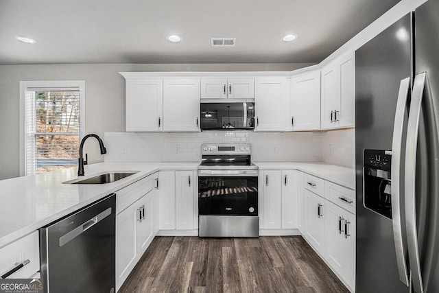 kitchen with tasteful backsplash, white cabinetry, sink, and stainless steel appliances