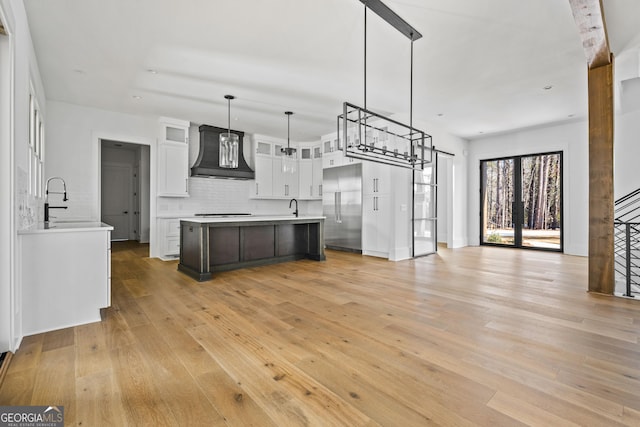 kitchen with custom exhaust hood, a center island, hanging light fixtures, stainless steel built in fridge, and white cabinets