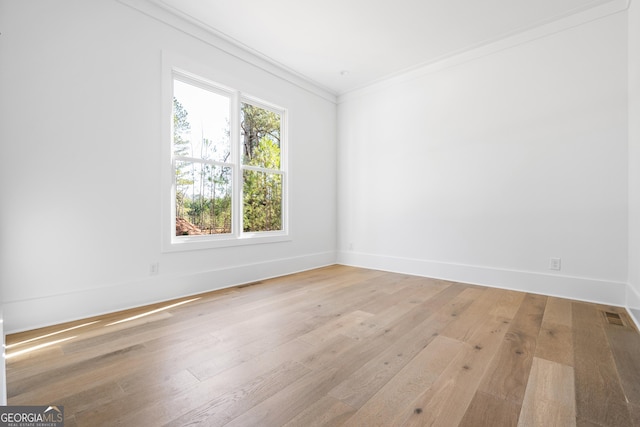 unfurnished room with ornamental molding and light wood-type flooring