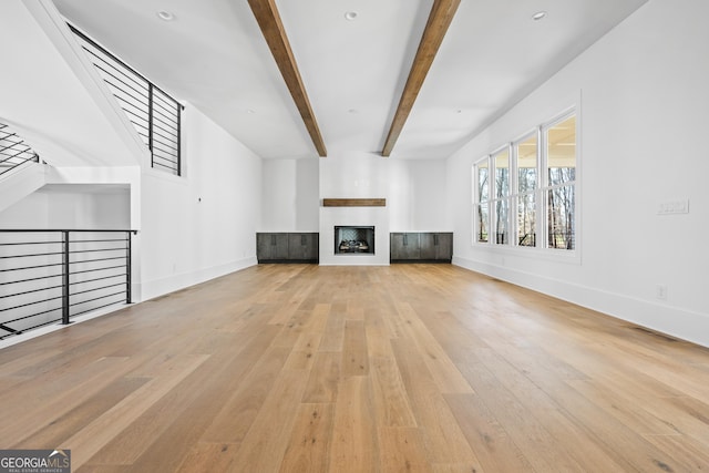 unfurnished living room with beam ceiling and light hardwood / wood-style floors