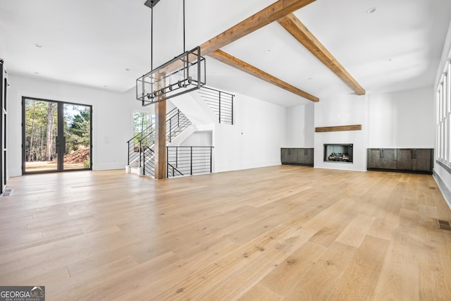 unfurnished living room featuring beam ceiling and light wood-type flooring