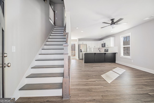 staircase featuring hardwood / wood-style floors, ceiling fan, and sink