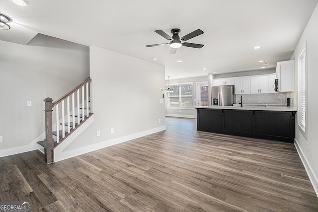 kitchen with backsplash, ceiling fan with notable chandelier, dark hardwood / wood-style floors, appliances with stainless steel finishes, and white cabinetry