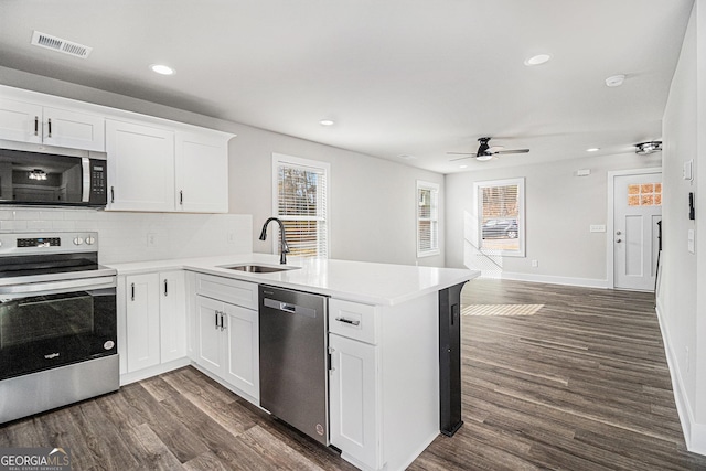 kitchen featuring dark hardwood / wood-style floors, white cabinetry, kitchen peninsula, and stainless steel appliances