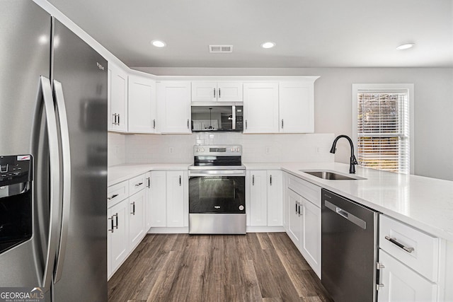 kitchen featuring appliances with stainless steel finishes, dark hardwood / wood-style flooring, tasteful backsplash, sink, and white cabinets