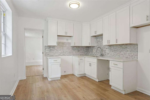 kitchen with decorative backsplash, light hardwood / wood-style flooring, white cabinets, and sink