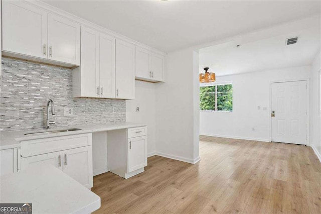 kitchen featuring white cabinets, backsplash, light hardwood / wood-style flooring, and sink