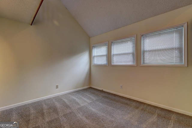 empty room with lofted ceiling, carpet floors, a textured ceiling, and baseboards