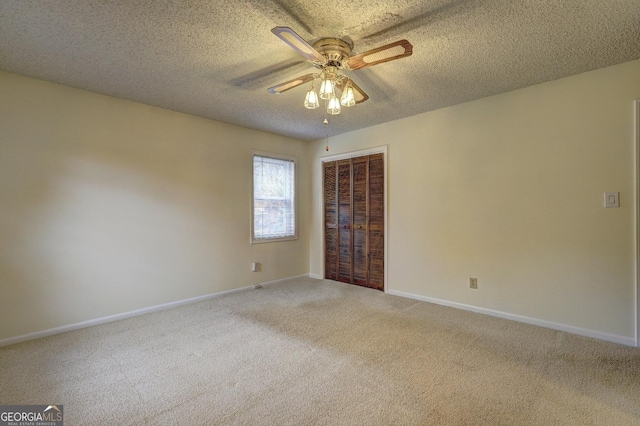 carpeted spare room with a textured ceiling, a ceiling fan, and baseboards