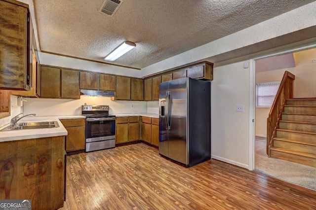 kitchen featuring under cabinet range hood, visible vents, light countertops, appliances with stainless steel finishes, and light wood finished floors