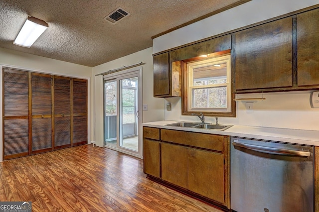 kitchen with light wood finished floors, light countertops, stainless steel dishwasher, and a sink