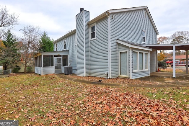 view of side of property with a sunroom, a chimney, and central AC unit