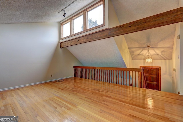 bonus room featuring a textured ceiling, wood finished floors, and vaulted ceiling with beams