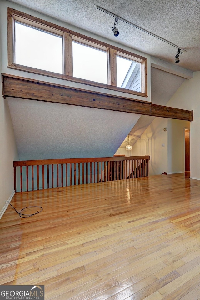 bonus room with light wood-type flooring, vaulted ceiling, and a textured ceiling