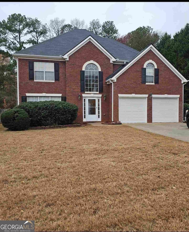 view of property featuring a garage and a front lawn